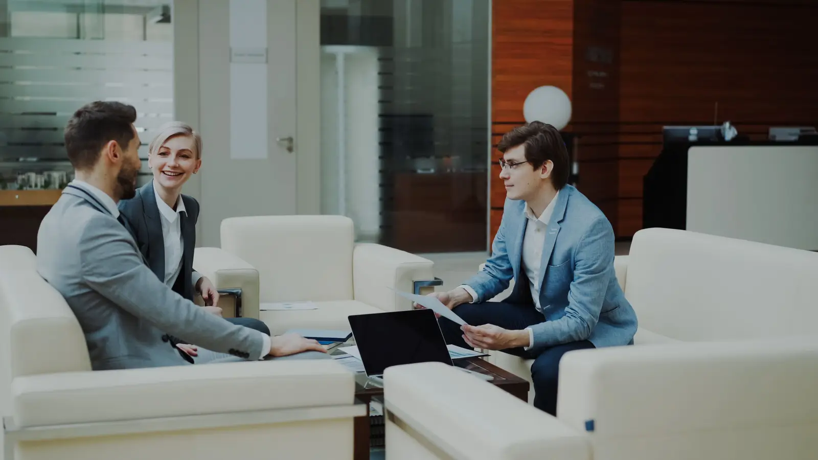 Three colleagues talking over documents in an office lounge